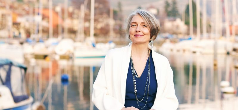 elegant older woman sitting in front of sailing boatsf
