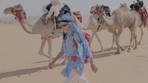 Camels and woman treking across the desert 